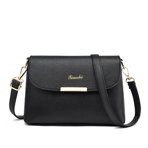 Minimalistische schwarze Umhängetasche aus Leder mit goldenem Verschluss auf weißem Grund