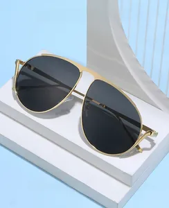 Détail de lunettes aviateur avec monture en métal doré et verres foncés sur socle