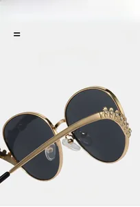 Detailed macro view of large gold metal frame sunglasses with crystal-embellished crown edges