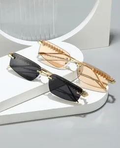 Detail of rimless rectangle sunglasses with textured gold metal temples and tinted lenses