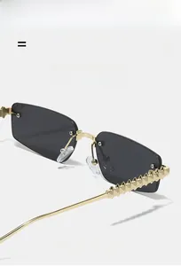Detail of rimless sunglasses with gold pyramid studs on temples and grey gradient lens