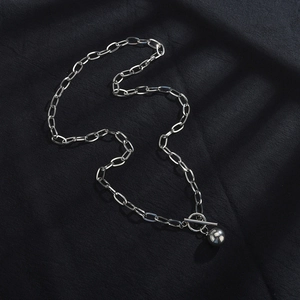 Macro detail of silver OT buckle and polished ball pendant on minimalist necklace