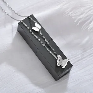 Detail of silver double butterfly pendants with matte and polished finishes on chain