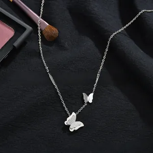 Detail of silver double butterfly necklace with zircon stones on textured black fabric