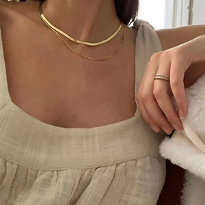 Set collana minimalista con catena a serpente dorata e anello indossato da una modella