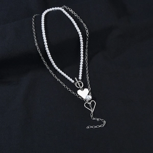 Detail showing double layer pearl necklace with silver heart charms and OT toggle clasp