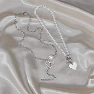 Double-layer pearl choker necklace with heart pendant on champagne satin fabric background