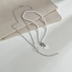 Detail of double-layer necklace with heart pendant, pearl strand and OT toggle clasp