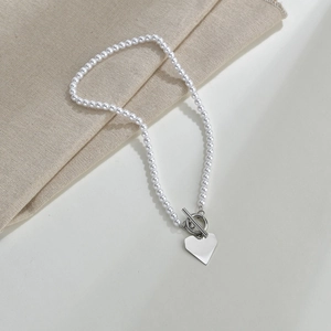 Close-up of double-layer pearl choker with silver heart pendant and OT toggle clasp closure