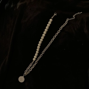 Detail of retro pearl and silver coin pendant necklace on black velvet background