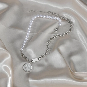 Vintage pearl and silver chain necklace with a retro relief medallion on champagne silk