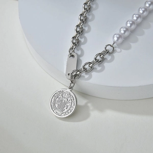 Macro detail of silver link chain necklace with white pearls and Saint Benedict medal