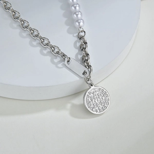 Close-up of mixed pearl and silver chain necklace with coin pendant on a stand