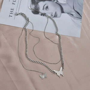 Detail of layered silver butterfly necklace featuring a chunky Cuban chain and fine link chain
