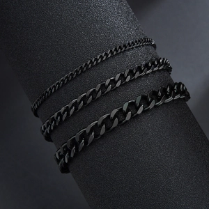 Détail de trois bracelets gourmette en acier titane noir sur un support d'exposition
