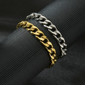 Polished gold and silver stainless steel Cuban link bracelets on black display stand