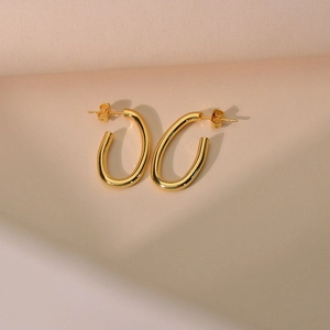 Macro shot of polished gold hollow oval hoop earrings with mirror finish detail