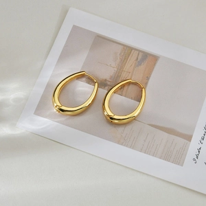 Detailed shot of thick oval gold earrings with a glossy finish on artistic card
