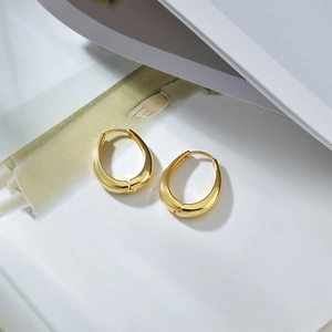 Close-up of polished golden U-shaped earrings on a white magazine with soft shadows