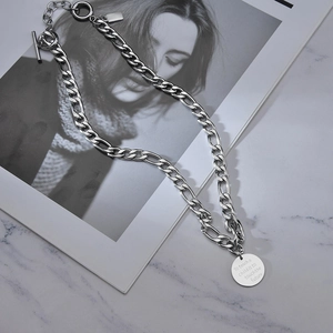 Silver chunky chain necklace with toggle clasp and engraved round pendant on marble
