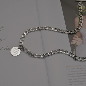 Close-up of engraved round pendant necklace with inspirational quote on magazine background