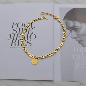 Golden Figaro chain necklace with a round quote pendant and toggle clasp closure