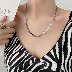 Detail of baroque pearl and metal link necklace with star and heart charms on neck
