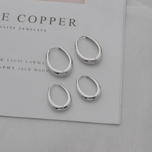 Minimalist silver oval hoop earrings in two sizes displayed on white magazine paper