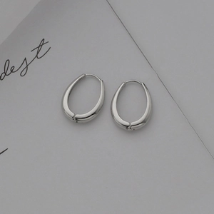 Minimalist silver oval hoop earrings with a polished mirror finish on white background