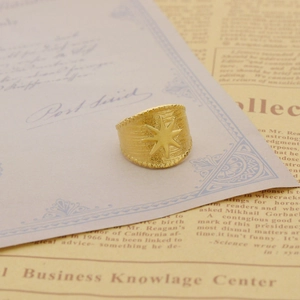 Vintage gold star adjustable compass ring with brushed texture on retro paper background