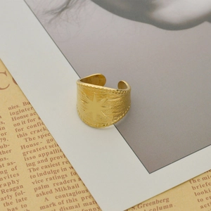 Vintage gold compass star open ring with hammered texture on newspaper background