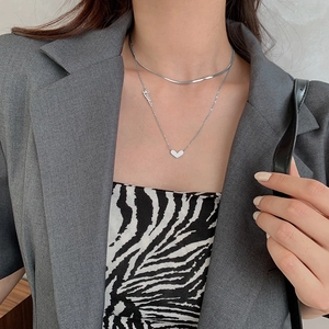 Collier double rang argenté avec pendentif cœur Love sur un mannequin en blazer gris
