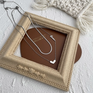 Détail du collier double couche argenté avec pendentif cœur, lettre Love et maille serpent