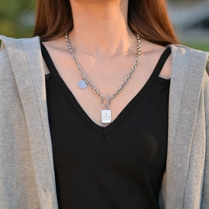 Detail of silver titanium steel necklace featuring OT buckle and engraved pendants