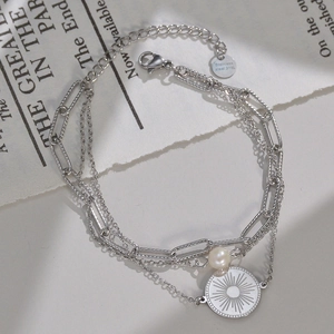 Détail d'un bracelet triple épaisseur en acier 316L avec perle et pendentif soleil