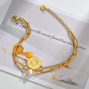 Détail du bracelet triple épaisseur en acier doré 14K avec médaille soleil et perle