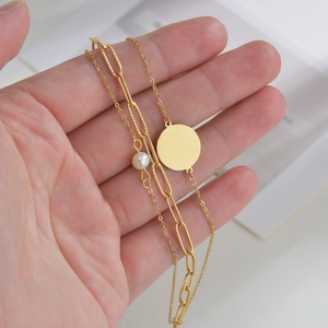 Vue détaillée du bracelet triple couche plaqué or 14K avec perle et pendentifs disques ronds