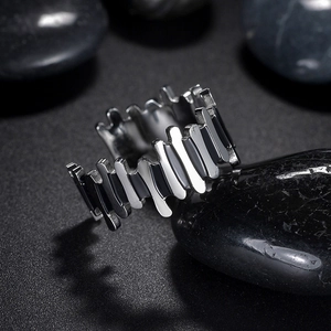 Minimalist stainless steel ring with irregular jagged edges on dark pebbles