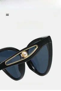 Detail of black butterfly sunglasses temple with gold triangle and faux pearl inlay