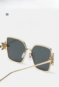 Detail of gold metal frame sunglasses with star engraving and gray lenses
