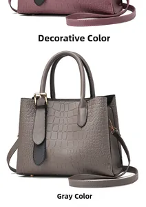 Detail view of grey faux crocodile embossed shoulder bag with round handle and metal buckle