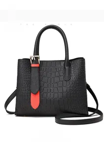 Front view of black crocodile pattern faux leather handbag with red trim and gold hardware