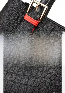 Detail of gold hardware and red stitching on a black crocodile embossed PU handbag