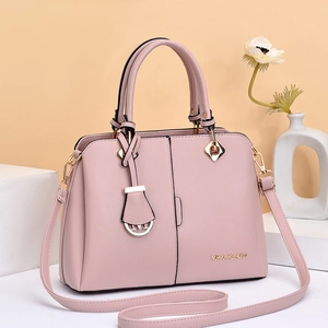 Pink lychee texture crossbody bag with gold hardware and top handles shown on display