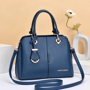 Detail of dark blue lychee grain leather handbag with gold logo on geometric base