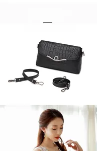 Detail of black crocodile pattern crossbody bag with silver hardware and dual straps