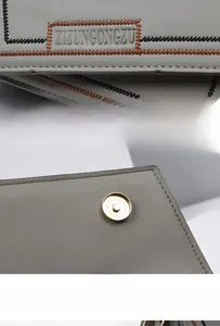 Close-up of brand logo embossing and magnetic snap closure on the gray PU leather bag