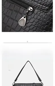 Detail of black crocodile pattern faux leather with silver zipper and adjustable strap