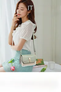 Detail of mint green crossbody bag with cat shaped metal clasp and chain strap