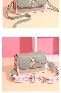 Detail of crossbody bag with cat-shaped metal lock and colorful embroidered strap